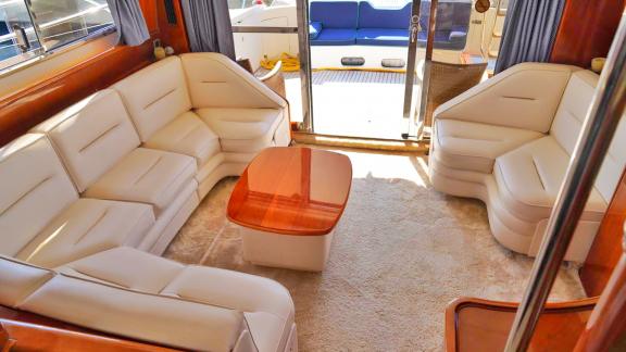 The salon seating area of the motor yacht Hadron is equipped with comfortable white sofas.